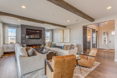Inspiration for a large transitional family room in Denver with light hardwood floors, a ribbon fireplace, a tile fireplace surround and a wall-mounted tv.