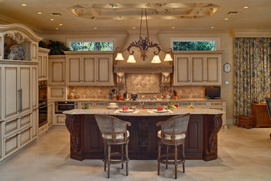 This is an example of a large traditional l-shaped open plan kitchen in New York with an undermount sink, raised-panel cabinets, beige cabinets, granite benchtops, beige splashback, stone tile splashback, panelled appliances and limestone floors.