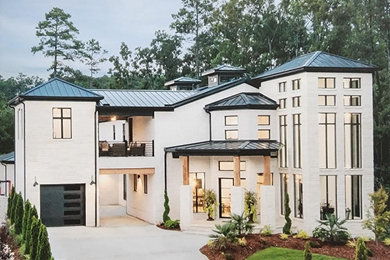 Huge white two-story stone house exterior photo in Little Rock with a hip roof, a metal roof and a black roof