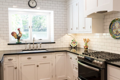 Mid-sized country u-shaped brown floor and shiplap ceiling enclosed kitchen photo in Grand Rapids with an undermount sink, shaker cabinets, white cabinets, soapstone countertops, white backsplash, black appliances, no island and black countertops