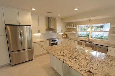 Inspiration for a large transitional l-shaped white floor eat-in kitchen remodel in Jacksonville with a farmhouse sink, shaker cabinets, white cabinets, granite countertops, white backsplash, subway tile backsplash, stainless steel appliances and an island