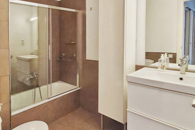 バルセロナにある中くらいなコンテンポラリースタイルのおしゃれなマスターバスルーム (白いキャビネット、ドロップイン型浴槽、白い壁、磁器タイルの床、横長型シンク、引戸のシャワー、洗面台1つ) の写真