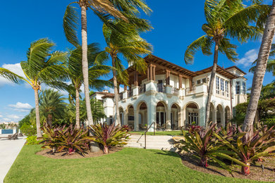 Inspiration for an expansive tropical two-storey stucco beige exterior in Miami with a flat roof.