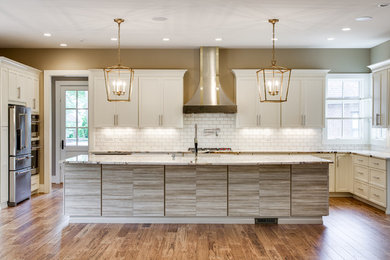 Inspiration for a large transitional u-shaped separate kitchen in Nashville with shaker cabinets, white cabinets, white splashback, subway tile splashback, stainless steel appliances, medium hardwood floors, with island and brown floor.