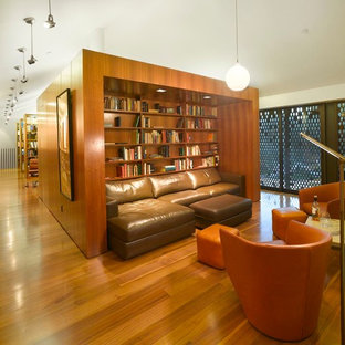 This is an example of an expansive modern home office and library in Los Angeles with a reading nook, white walls, medium hardwood flooring and a freestanding desk.