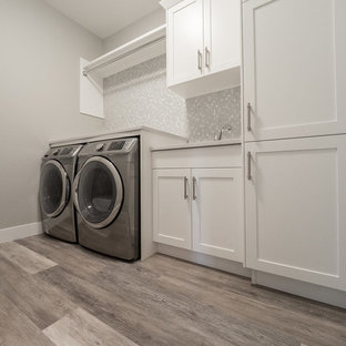 Design ideas for a large classic single-wall separated utility room in Edmonton with a double-bowl sink, recessed-panel cabinets, white cabinets, composite countertops, grey walls, vinyl flooring, a side by side washer and dryer and multi-coloured floors.