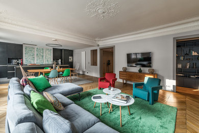 Cette photo montre une très grande salle de séjour tendance ouverte avec un mur beige, parquet clair, une cheminée standard, un manteau de cheminée en pierre et un téléviseur fixé au mur.
