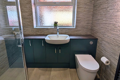 Photo of a medium sized modern family bathroom in Other with flat-panel cabinets, green cabinets, a corner shower, a one-piece toilet, multi-coloured tiles, porcelain tiles, blue walls, laminate floors, a built-in sink, laminate worktops, brown floors, a hinged door, grey worktops, a single sink and a built in vanity unit.