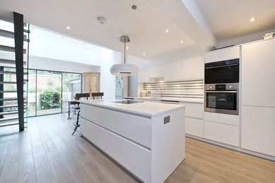 This is an example of a medium sized contemporary single-wall kitchen/diner in London with a submerged sink, flat-panel cabinets, white cabinets, quartz worktops, light hardwood flooring, an island and beige floors.