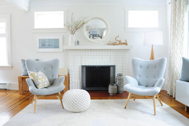 Mid-sized beach style formal and open concept medium tone wood floor living room photo in Vancouver with white walls, a standard fireplace, a brick fireplace and no tv
