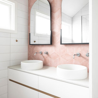 Foto på ett mellanstort funkis vit badrum med dusch, med släta luckor, vita skåp, en dusch i en alkov, en toalettstol med hel cisternkåpa, rosa kakel, porslinskakel, vita väggar, klinkergolv i porslin, ett fristående handfat, bänkskiva i kvarts, rosa golv och dusch med gångjärnsdörr