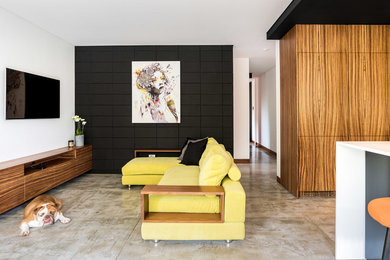 Small contemporary open concept living room in Sydney with black walls, concrete floors and a wall-mounted tv.