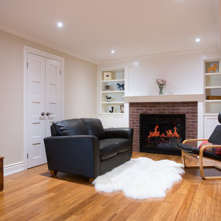 Imagen de sótano en el subsuelo bohemio con suelo de bambú, chimenea tradicional y marco de chimenea de ladrillo