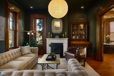 コロンバスにある高級な中くらいなトラディショナルスタイルのおしゃれなリビング (緑の壁、無垢フローリング、標準型暖炉、石材の暖炉まわり、テレビなし、茶色い床) の写真