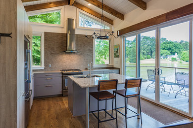Example of a mid-sized minimalist l-shaped light wood floor open concept kitchen design in Charlotte with a double-bowl sink, flat-panel cabinets, gray cabinets, quartz countertops, gray backsplash, stone tile backsplash, stainless steel appliances and an island