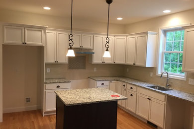 Kitchen - traditional light wood floor kitchen idea in Boston with an undermount sink, recessed-panel cabinets, white cabinets, granite countertops, beige backsplash, subway tile backsplash, stainless steel appliances and an island