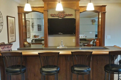 Example of a mid-sized classic galley dark wood floor and brown floor seated home bar design in Other with a drop-in sink, raised-panel cabinets, dark wood cabinets and granite countertops