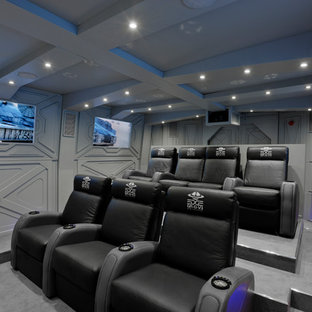 Large urban enclosed carpeted and gray floor home theater photo in Hertfordshire with gray walls