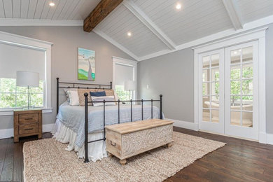 Ejemplo de dormitorio principal de estilo de casa de campo grande con paredes grises, suelo de madera en tonos medios, suelo marrón y machihembrado