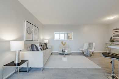 Modelo de salón abierto tradicional renovado de tamaño medio con paredes grises, suelo laminado y suelo gris