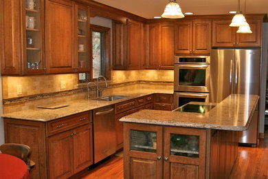 Elegant l-shaped medium tone wood floor eat-in kitchen photo in St Louis with an undermount sink, medium tone wood cabinets, granite countertops, beige backsplash, stainless steel appliances and an island