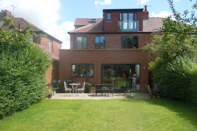 This is an example of a mid-sized contemporary one-storey brick red exterior with a flat roof.