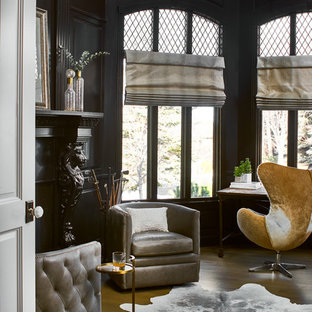 Inspiration för ett stort vintage hemmabibliotek, med svarta väggar, mellanmörkt trägolv, en standard öppen spis, en spiselkrans i trä, ett fristående skrivbord och brunt golv