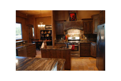 Bild på ett amerikanskt kök, med en undermonterad diskho, luckor med upphöjd panel, skåp i slitet trä, granitbänkskiva, flerfärgad stänkskydd, rostfria vitvaror, klinkergolv i porslin och en köksö