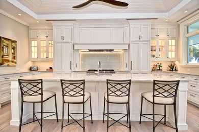 Inspiration for a large transitional eat-in kitchen in Tampa with an undermount sink, beaded inset cabinets, white cabinets, quartzite benchtops, white splashback, glass tile splashback, panelled appliances, light hardwood floors, with island, white floor and white benchtop.