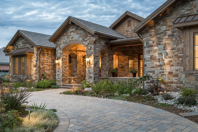 Photo of a traditional one-storey house exterior in Denver with stone veneer, a gable roof and a tile roof.