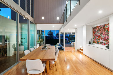 This is an example of a contemporary dining room in Sydney with white walls, light hardwood floors and brown floor.