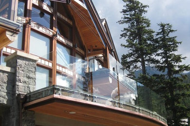 Large rustic three-story stone exterior home idea in Vancouver