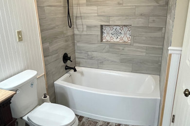 Inspiration for a mid-sized french country master gray tile and wood-look tile porcelain tile, brown floor, single-sink and wallpaper bathroom remodel in Denver with medium tone wood cabinets, marble countertops, a niche and a floating vanity