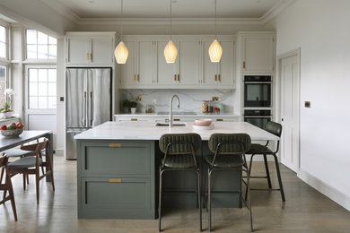 Inspiration for a medium sized classic grey and white single-wall open plan kitchen in London with a single-bowl sink, shaker cabinets, grey cabinets, quartz worktops, engineered quartz splashback, stainless steel appliances, medium hardwood flooring, an island and white worktops.