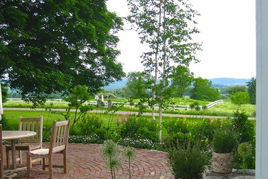 Example of a mid-sized country backyard brick patio design in DC Metro with no cover