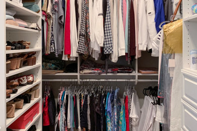 Example of a mid-sized beach style gender-neutral medium tone wood floor walk-in closet design in Other with raised-panel cabinets and white cabinets
