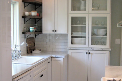 Inspiration for a small cottage galley medium tone wood floor and brown floor enclosed kitchen remodel with a drop-in sink, shaker cabinets, white cabinets, laminate countertops, white backsplash, subway tile backsplash, white appliances, no island and white countertops