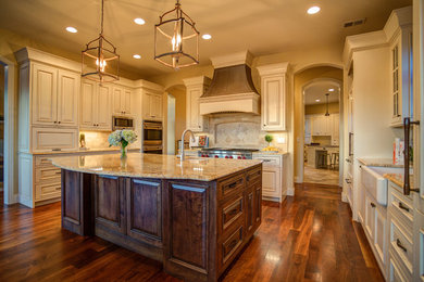 Eat-in kitchen - traditional u-shaped medium tone wood floor eat-in kitchen idea in Denver with a farmhouse sink, beaded inset cabinets, white cabinets, granite countertops, beige backsplash, stone tile backsplash, paneled appliances and an island