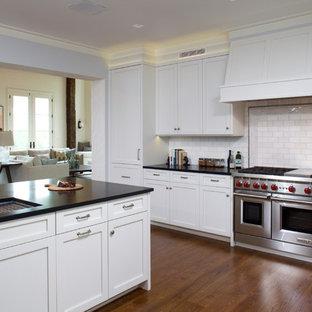 Photo of a large transitional u-shaped kitchen pantry in New York with an undermount sink, shaker cabinets, white cabinets, soapstone benchtops, white splashback, subway tile splashback, panelled appliances, medium hardwood floors and a peninsula.