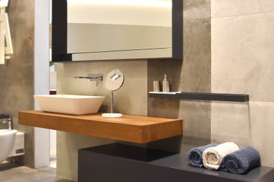 Foto di un bagno di servizio minimal con ante lisce, ante grigie, piastrelle beige, piastrelle in gres porcellanato, top in legno, top marrone e mobile bagno sospeso