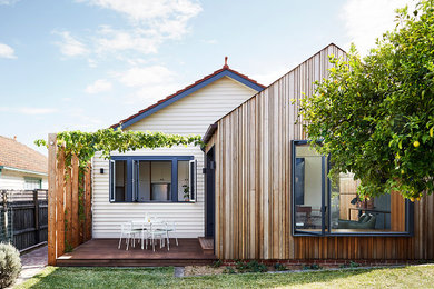 Small contemporary one-storey beige house exterior in Melbourne with wood siding, a mixed roof and a gable roof.