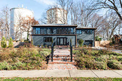 Cette photo montre une grande façade de maison grise tendance en panneau de béton fibré et planches et couvre-joints à un étage avec un toit à deux pans, un toit en métal et un toit gris.