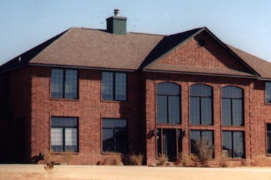 Inspiration for a large timeless red two-story brick house exterior remodel in Oklahoma City with a hip roof and a shingle roof