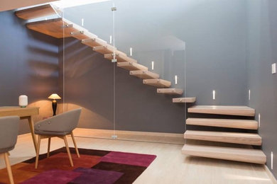 Foto de escalera suspendida contemporánea con escalones de madera y barandilla de vidrio