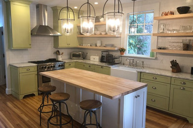 Mid-sized country u-shaped eat-in kitchen in Other with a farmhouse sink, shaker cabinets, green cabinets, granite benchtops, white splashback, subway tile splashback, stainless steel appliances, medium hardwood floors, with island, brown floor and grey benchtop.
