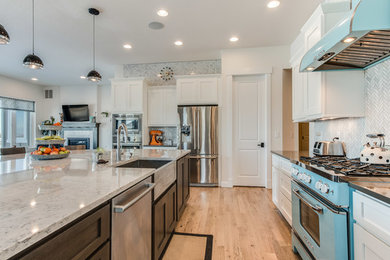 Example of a large transitional l-shaped light wood floor open concept kitchen design in Denver with a farmhouse sink, shaker cabinets, white cabinets, marble countertops, gray backsplash, matchstick tile backsplash, stainless steel appliances and an island