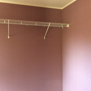 Modelo de armario vestidor de mujer y papel pintado, minimalista, de tamaño medio, con armarios con paneles lisos, puertas de armario de madera oscura, suelo de madera en tonos medios, suelo marrón y papel pintado