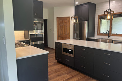 Example of a mid-sized trendy eat-in kitchen design in Other with shaker cabinets, black cabinets, quartz countertops, white backsplash, an island and white countertops