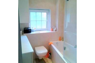 Réalisation d'une petite salle d'eau design avec un placard à porte affleurante, des portes de placard blanches, une baignoire encastrée, WC suspendus, un carrelage de pierre, un mur beige et une vasque.