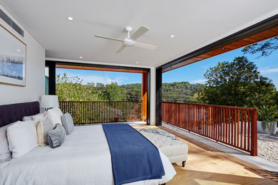 Contemporary master bedroom in Sydney with white walls, medium hardwood floors and brown floor.